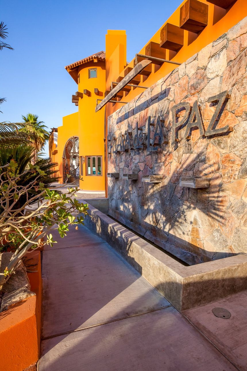 Muro de piedra con el letrero de Playa de La Paz